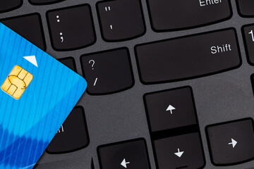 Credit cards stacked on a black laptop keyboard. Photo taken under artificial, soft light