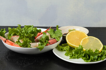 Natural raw scallop with boiled shrimp in the sink in a ceramic bowl with lettuce leaves and sauce on a dark background.