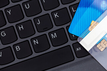 Credit cards stacked on a black laptop keyboard. Photo taken under artificial, soft light