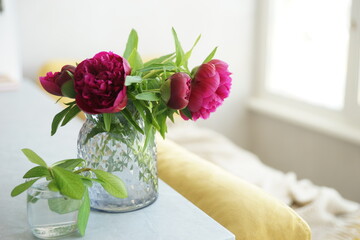 Bouquet of red peonies in a vase on the table
