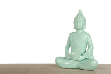 Beautiful ceramic Buddha sculpture with burning candle on wooden table against grey background. Space for text