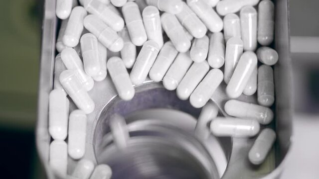 Capsule pills are falling into a hole in the conveyor