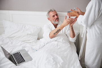 Bearded European adult man resting on the bed in home apartment