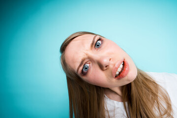 Close-up photo, fish eye. The girl is surprised and opening her mouth tilts her head to the side looking at the camera