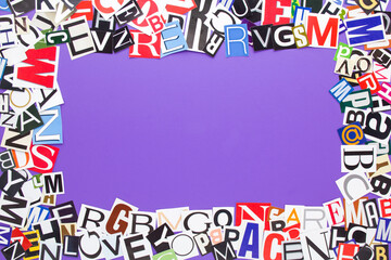 Alphabet letters cutting from paper magazine on purple background with copy space for text. Colorful abstract collage from clippings with newspaper magazine letters.