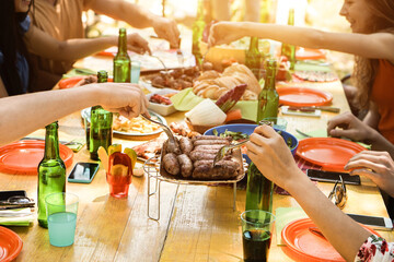 Group of people having fun at barbecue party outdoors in terrace - Focus on fork sausages