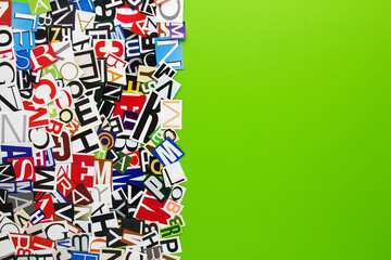 Alphabet letters cutting from paper magazine on green background with copy space for text. Abstract collage from clippings with newspaper magazine letters.