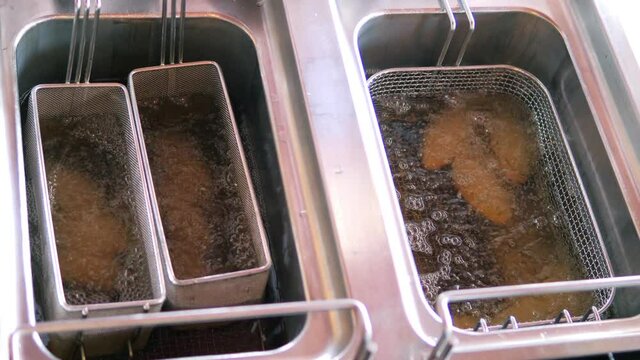 Close-up. The meat dish is placed in a deep fryer.