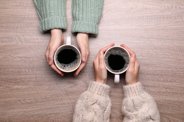 Women with cups of coffee at wooden table, top view - Powered by Adobe