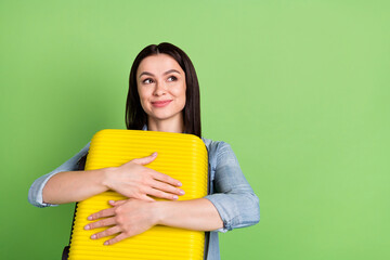 Photo of young dreamy smiling pretty girl look copyspace hug embrace luggage isolated on green color background