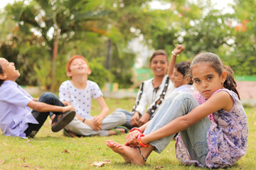Group of kids bulling girl at park during summer camp - Little girl looking camera, sitting lonely...