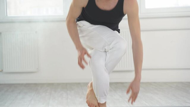 Man working out indoors, stand in Eagle Pose, Garudasana, confident experienced male in sportswear look at camera while keeping balance.