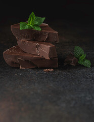 Piece chocolate with mint on a dark background.