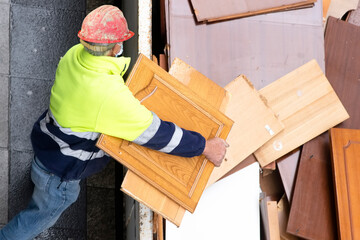bricklayer worker in motion blur in construction site depositing rubble in container for pickup by...