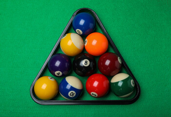 Plastic rack with billiard balls on green table, top view