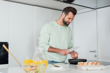 Fototapeta na wymiar man preparing breakfast from chicken eggs near orange juice on blurred foreground
