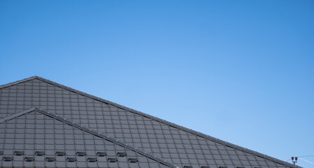 Brown corrugated metal profile roof installed on a modern house. The roof of corrugated sheet. Roofing of metal profile wavy shape. Modern roof made of metal. Metal roofing.