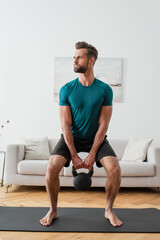 Obraz premium barefoot sportsman training with kettlebell at home