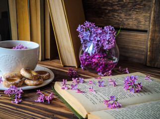 a bouquet of lilacs and a white cup of tea on a wooden background