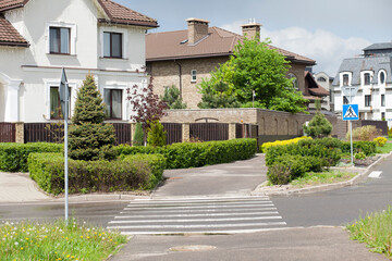 Pedestrian crossing through a small street in an elite residential area. Summer time. There is no one on the street.