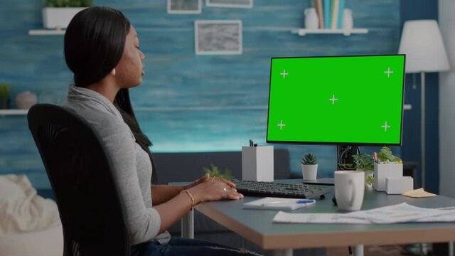 African american student sitting at desk working remote from home during virtual videocall meeting conference. Black woman browsing school information using mock up green screen chroma key computer