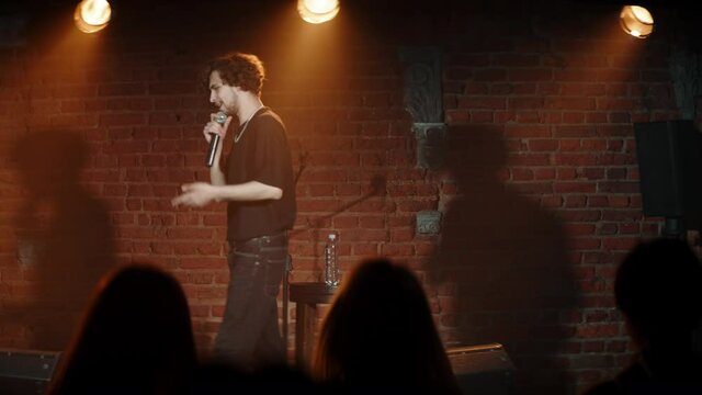 Young Caucasian male host of the stand-up show introducing Caucasian female comedian and leaving stage. Shot with ARRI Alexa Mini LF with 2x anamorphic lens