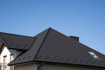 Fototapeta premium Brown corrugated metal profile roof installed on a modern house. The roof of corrugated sheet. Roofing of metal profile wavy shape. Modern roof made of metal. Metal roofing.
