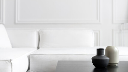 Grey vases on black tea table near couch