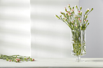 Fresh flowers on white wooden table and wall background with shadow. Free space for your decoration.