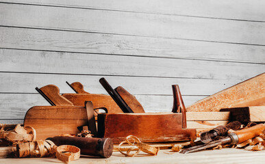 Photo of wooden old fashioned planes with carving chisels laying on workbench table.