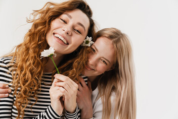 Young white two women hugging and smiling while posing with flowers