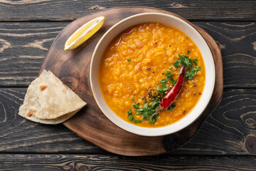 Masoor dal. Indian spicy red lentil soup, roti (chapati) are on brown wooden table. - obrazy, fototapety, plakaty