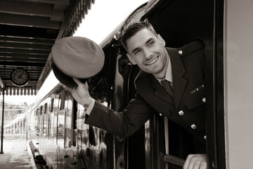 Fototapeta na wymiar Handsome british officer in vintage ww2 uniform on train waving at someone through the door window with hat, smiling