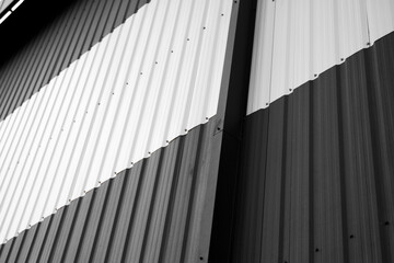 Details of black and white corrugated iron sheet used as a facade of a warehouse or factory. Texture of a seamless corrugated zinc sheet metal aluminum facade. Architecture. Metal texture.