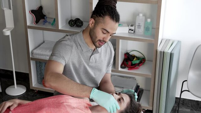 Physiotherpist doing jaw massage on female patient