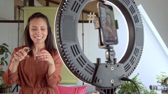 Female influencer testing perfume in front of smartphone camera