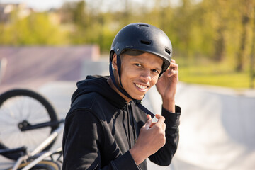A young boy sits on a ramp at a skatepark with his bike lying wheel up behind him. The guy has...