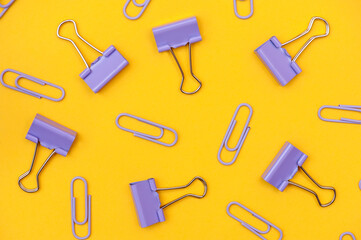 Collection of purple paper clips on a yellow background. Background from stationery