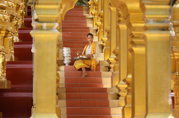 Fototapeta premium Myanmar women holding flowers at a temple. Southeast Asian young girls with burmese traditional dress visiting a Buddihist temple