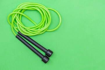 Sports rope for jumping green on a green background, top view close-up. The concept is a healthy lifestyle. 