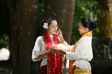 Obraz premium Two Myanmar women holding flowers at a temple. Southeast Asian young girls with burmese traditional dress visiting a Buddihist