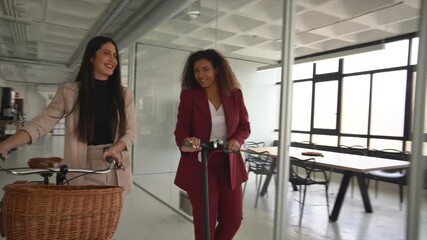 Businesswomen arriving at corworking space, pushing bicycles - Powered by Adobe