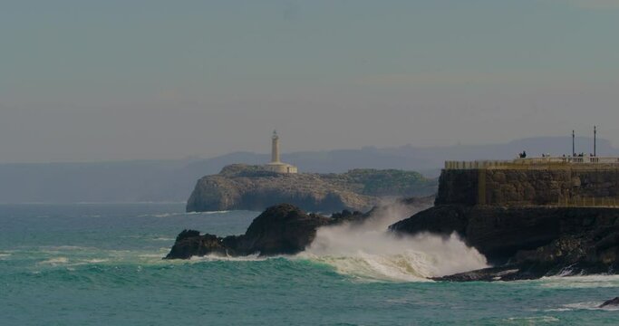 Faro de Mouro lighthouse in Santander, Spain on windy day with waves breaking in foreground. Static shot.