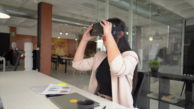 Businesswoman sitting at desk using virtual reality simulator