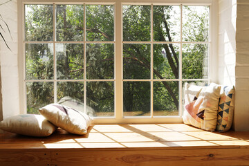 Modern window with pillows, trees and sky behind