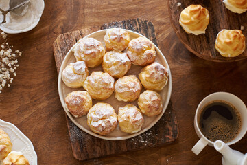 Homemade profiteroles with powdered sugar. Top view, wooden background.