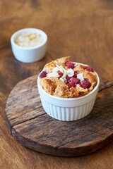 Bread pudding with raspberry. Side view, wooden background.