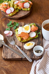 Fototapeta na wymiar Spinach waffles with salmon, egg and radish. Side view, wooden background.