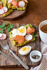 Spinach waffles with salmon, egg and radish. Side view, wooden background.