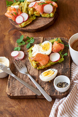 Fototapeta na wymiar Spinach waffles with salmon, egg and radish. Side view, wooden background.